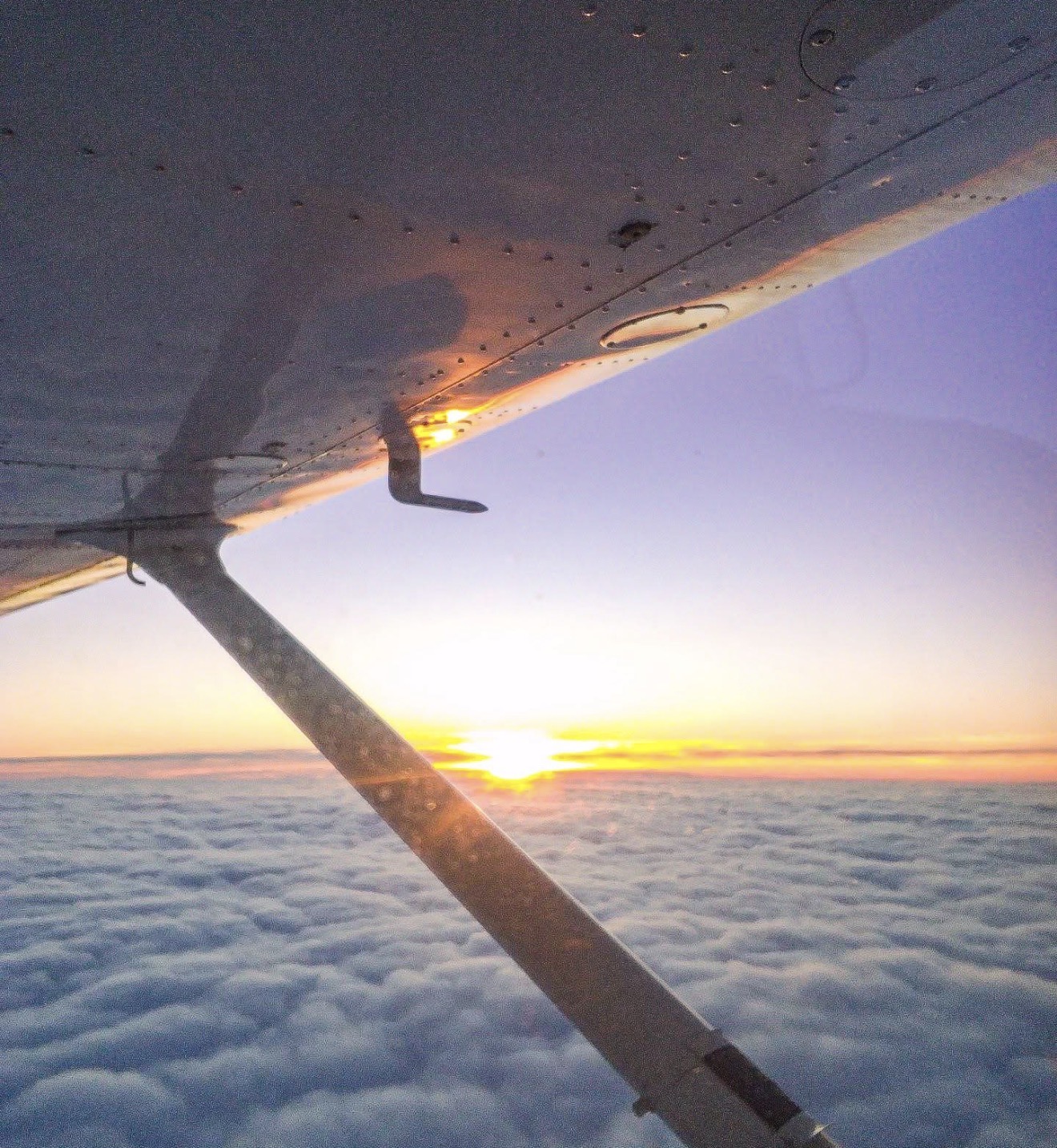 Sunset view from a small aircraft wing above the clouds
