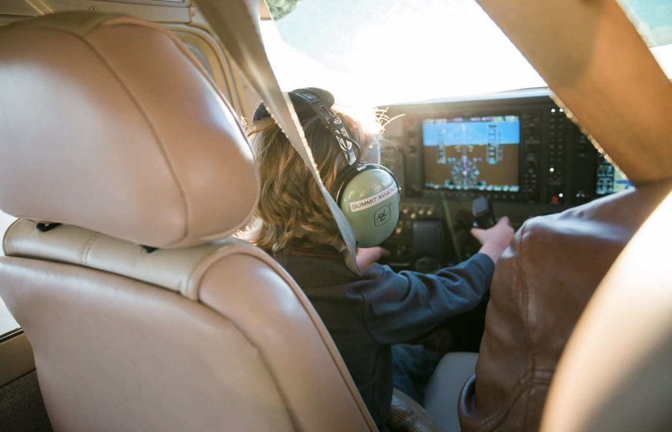 Child in the cockpit wearing Summit Aviation headset at the controls