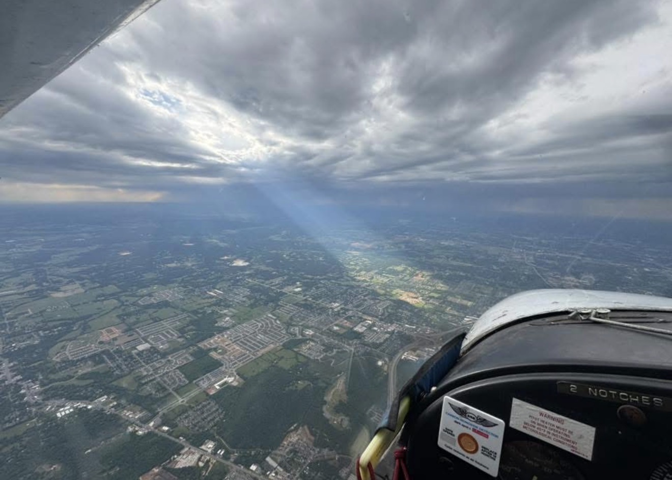 Aerial view through cockpit window with sunbeams over the landscape